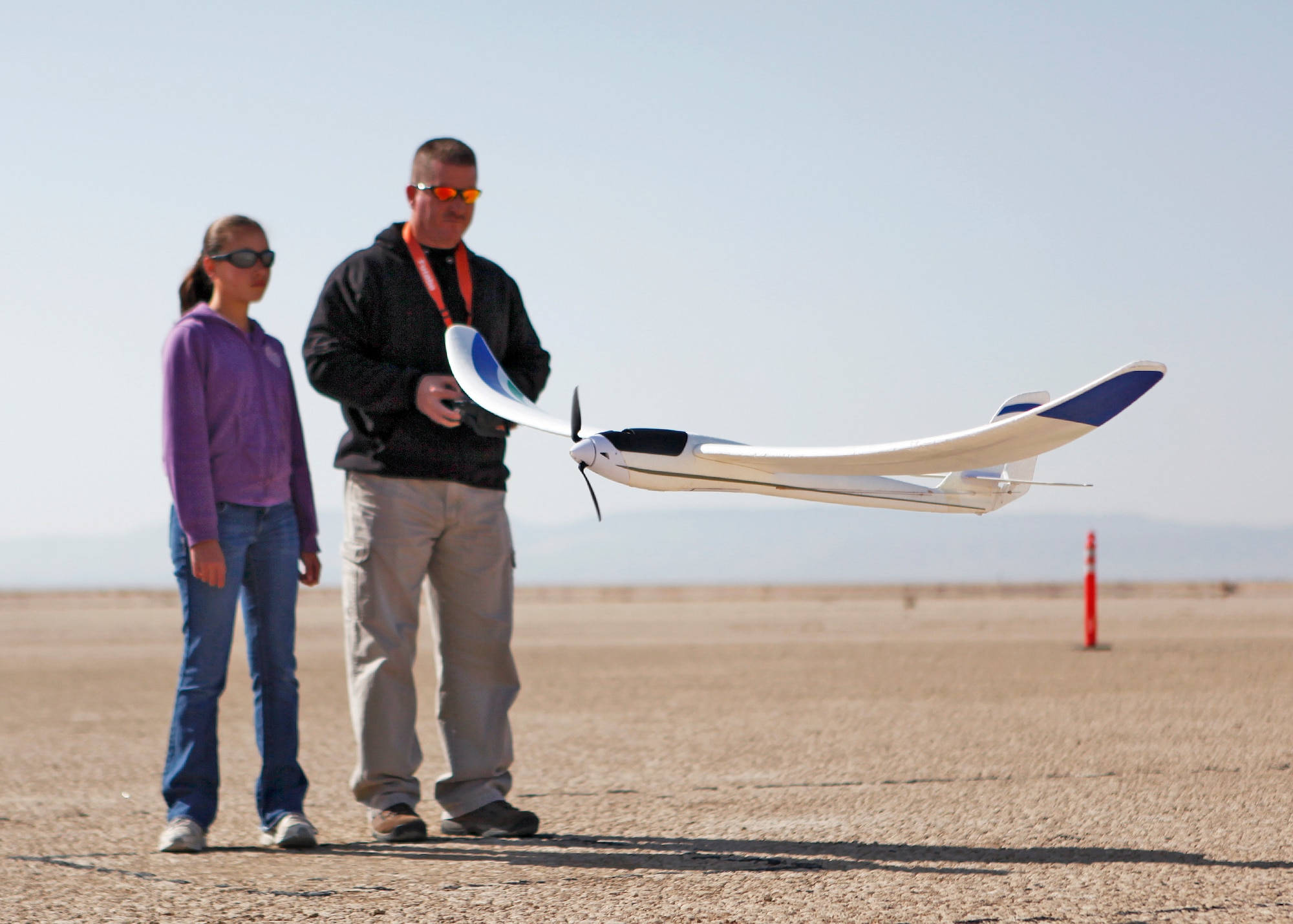 Master Sgt. Anthony Accurso flies his radio controlled Parkzone Radian powered glider for quick low approach over the Rosamond Dry Lake Bed before handing
the transmitter over to his daughter Evelyn Feb. 26. Sergeant Accurso is assigned to the 412th Maintenance Squadron as the NCO in charge of Aerospace Ground Equipment Flight and is the Muroc Model Master club safety coordinator. The club holds meetings every second Tuesday of each month for those interested in joining. (U.S. Air Force photo by Jet Fabara)
