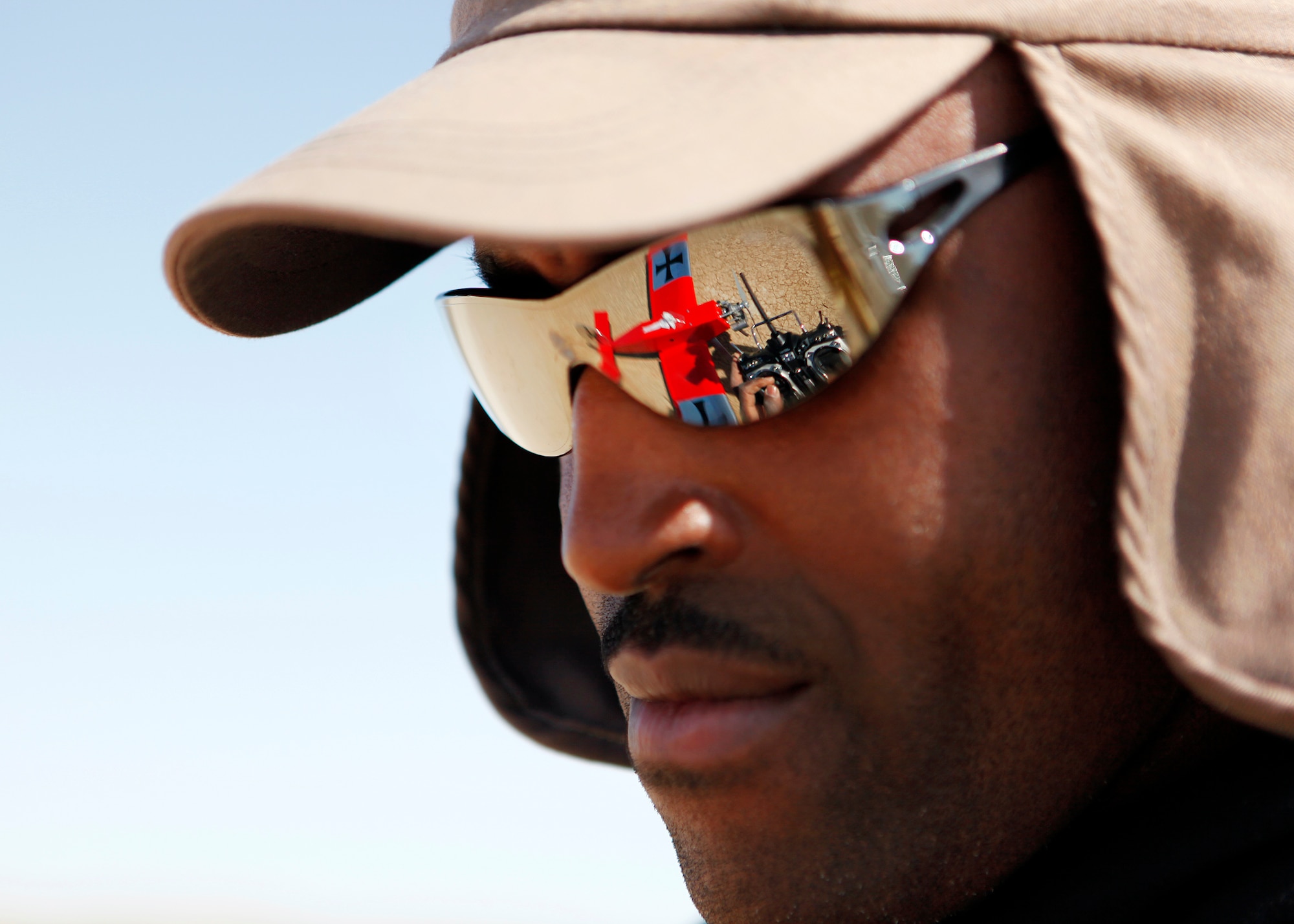 Through Tech. Sgt. Antwain Mallory's sunglasses, a reflection of his hands can be seen performing a preflight check on his bright red radio controlled Sweet N Low mid-stick aircraft with the use of his hand-held transmitter on the Rosamond Dry Lake Bed Feb. 26. Sergeant Mallory is a 412th Aircraft Maintenance Squadron NCOIC of F-35 Aerospace Ground Equipment and Muroc Model Master club member who is one of the many aviation enthusiasts who fly RC airplanes at the MMM flying site. (U.S. Air Force photo by Jet Fabara)