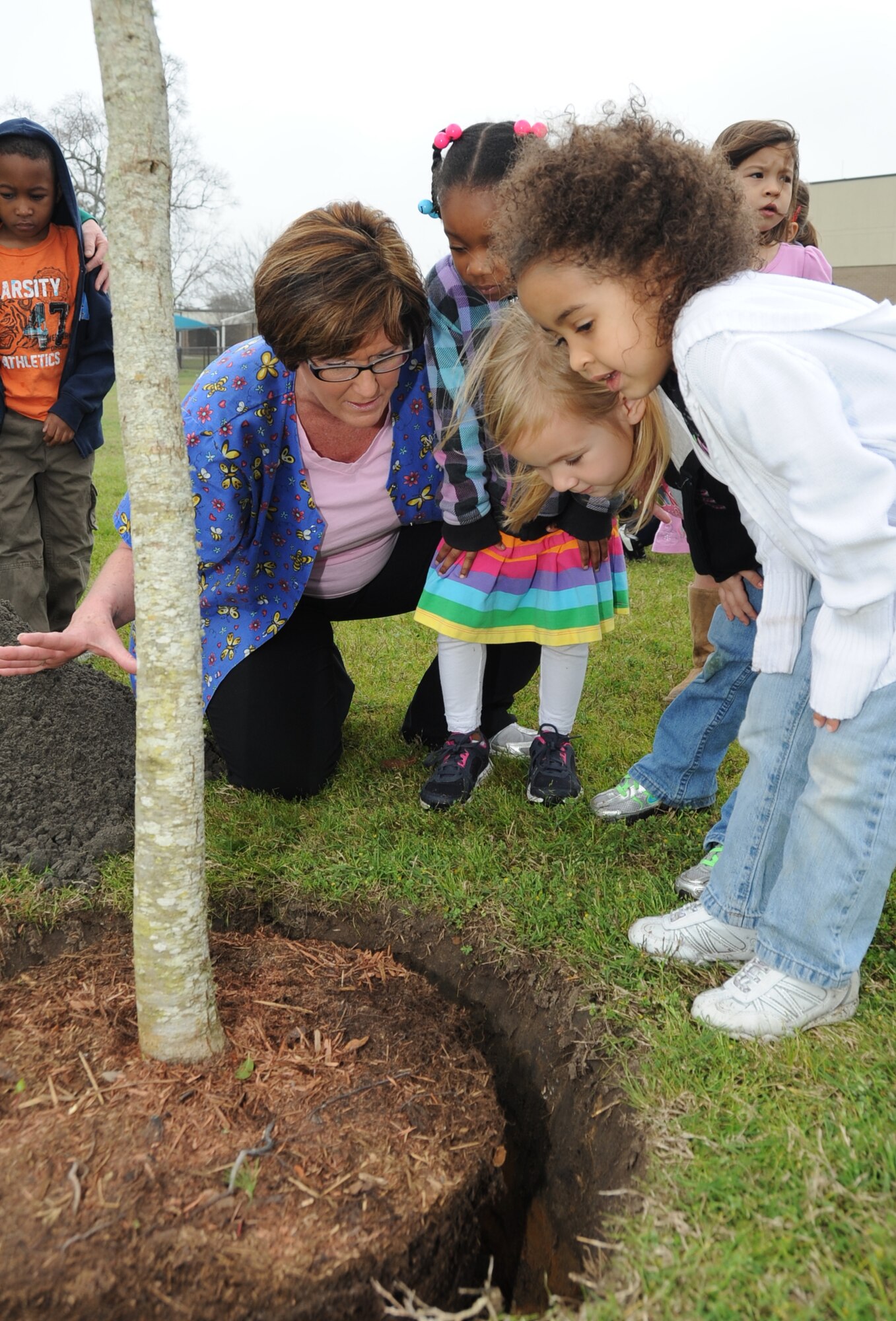 Brigid Suter, Child Development Center caregiver room lead, explains the planting process of the live oak tree to a few of the children in her class Feb. 23, 2012 at the CDC, Keesler Air Force Base, Miss.  The tree was planted during an Earth Arbor Day ceremony by Brig. Gen. Andrew Mueller, 81st Training Wing commander and four-to-five year old children from the CDC.  (U.S. Air Force photo by Kemberly Groue)