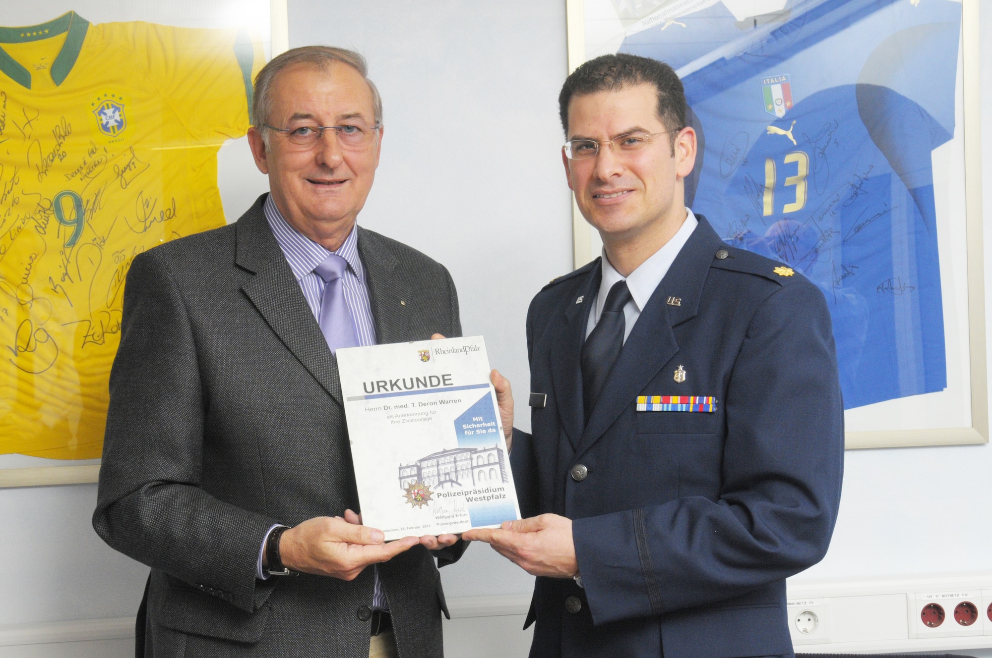 Maj. Deron Warren receives the German Auszeichnung für Zivilcourage award for civil courage from Polizeipräsidium (commissioner) Wolfgang Erfurt, Chief of Polizei for Kaiserslautern, Germany, during a ceremony at the city police headquarters Feb. 28, 2012. Warren is a emergency room physician for the Landstuhl Regional Medical Facility and he received this award for stopping a would-be robbery in progress outside of a local restaurant. (U.S. Air Force photo/Staff Sgt. Travis Edwards)