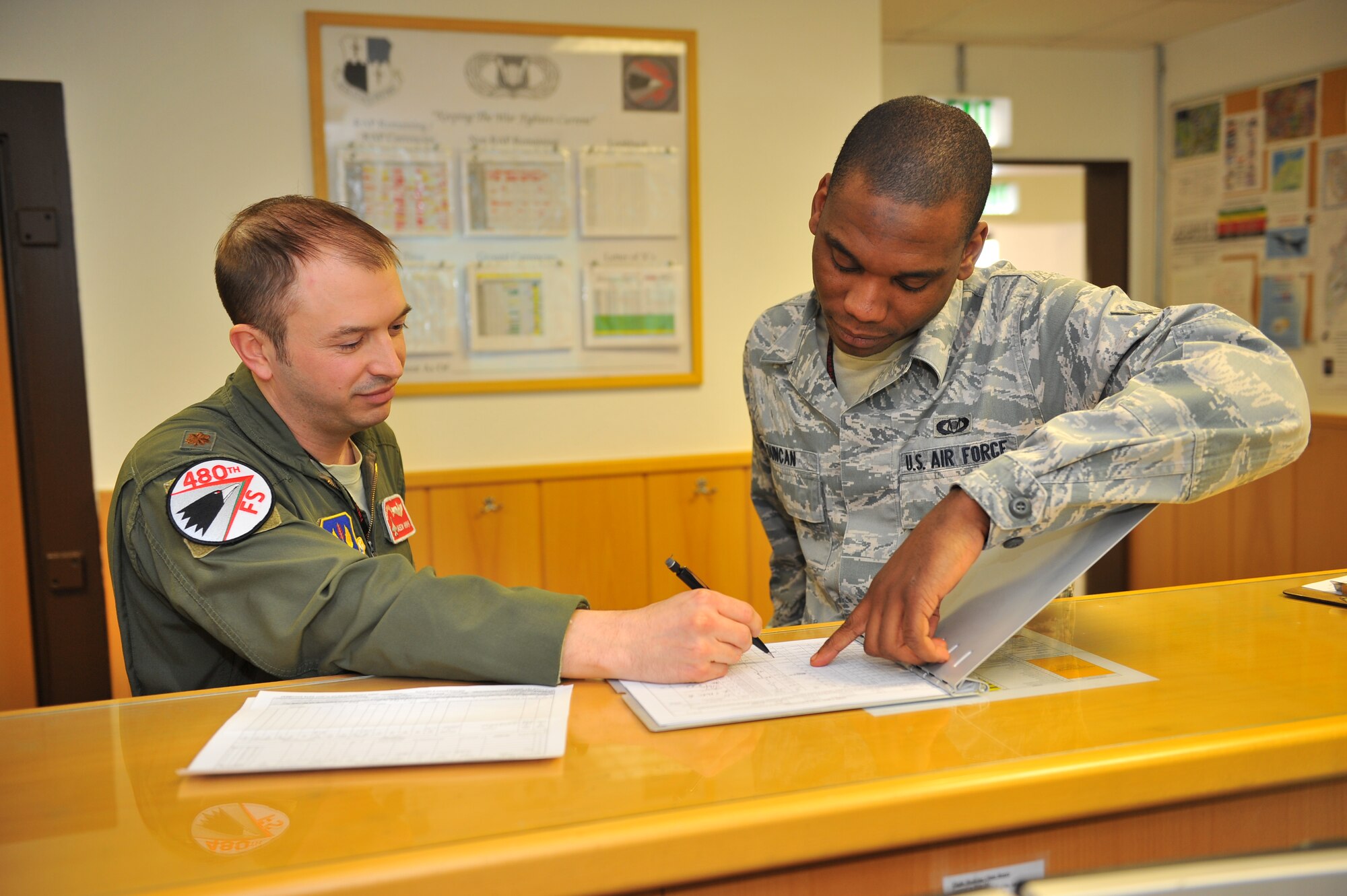 SPANGDAHLEM AIR BASE, Germany – Maj. Jason Hrynyk, left, 480th Fighter Squadron operations desk supervisor, and Airman 1st Class Keith Duncan, 480th FS aviation resource management apprentice, fill out a flight authorization form inside Bldg. 108 here Feb. 21 before adding the pilots’ training hours to their records. Twelve Airmen work at the squadron’s operations desk and are responsible for coordinating with base operations, weather operations and aircraft maintenance to ensure flight operations run smoothly. The operations desk is also responsible for gathering and organizing flight information to help log flight hours and brief pilots before, during and after flights. (U.S. Air Force photo by Airman 1st Class Dillon Davis/Released)