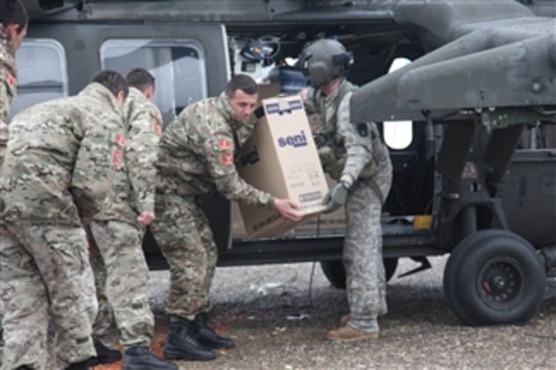 A U.S. Army soldier (right) hands a box of humanitarian relief supplies to a Montenegrin soldier during a resupply mission in Mojkovac, Montenegro, on Feb. 24, 2012.  U.S. troops and UH-60 Black Hawk helicopters with the 1st Battalion, 214th Aviation Regiment, 12th Combat Aviation Brigade traveled from Germany at the request of the Montenegrin government to assist residents stranded by heavy snowfall and unable to receive food, fuel or medical assistance.  