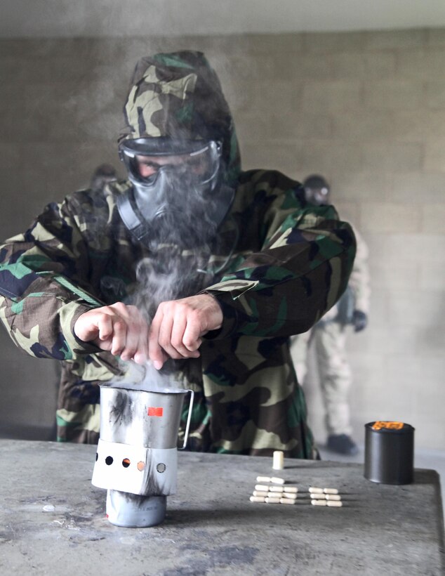 Sergeant Travis Tabor, chemical biological radiological nuclear instructor, Command Element, 15th Marine Expeditionary Unit, releases CS gas capsules (tear gas) during an Individual Protective Equipment Confidence Exercise at the 33 Area gas chamber, Feb. 28. Marines and sailors from the 15th MEU were completing annual training that built confidence in their equipment and taught the servicemembers survival techniques in case of a CBRN threat.