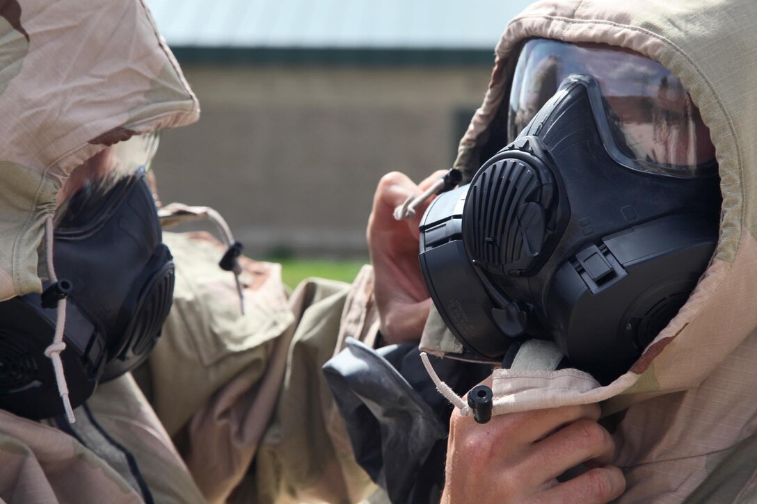 Marines from the Command Element, 15th Marine Expeditionary Unit, suit up in Mission Oriented Protective Posture suits during an Individual Protective Equipment Confidence Exercise at the 33 Area gas chamber, Feb. 28.  The MOPP suits are designed to protect the wearer from field concentrations of chemical, biological, radiological and nuclear hazards. The servicemembers were completing annual training that built confidence and taught the servicemembers survival techniques in case of a CBRN threat.