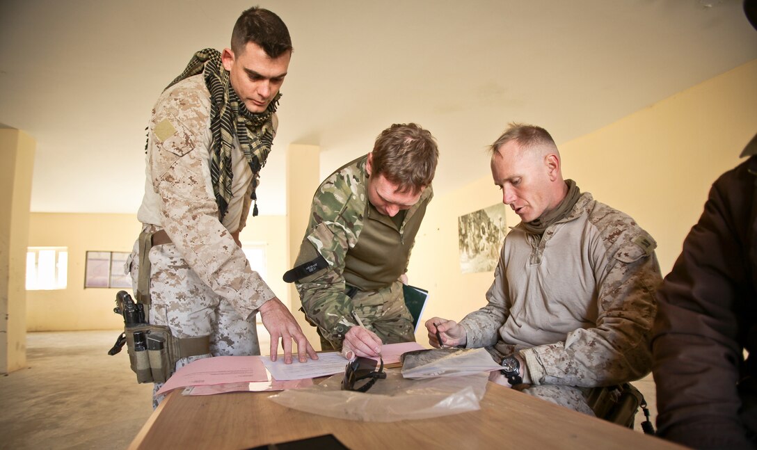 British Army Major Matt Helsby, acting officer-in-charge for the Afghan Local Police mentoring unit in southern Nahr-e-Saraj District, verifies and signs the pay roster as Staff Sgt. Christopher Stephens (left) and Capt. Chad Lowry (right), pay agents from Regional Command Southwest’s Afghan National Security Force Development Team, assist and wait to begin handing out payments at the Pan Kalay Police Station in Nahr-e-Saraj District, Feb. 3. Stephens and Lowry travel throughout Helmand province ensuring local policemen are properly paid.