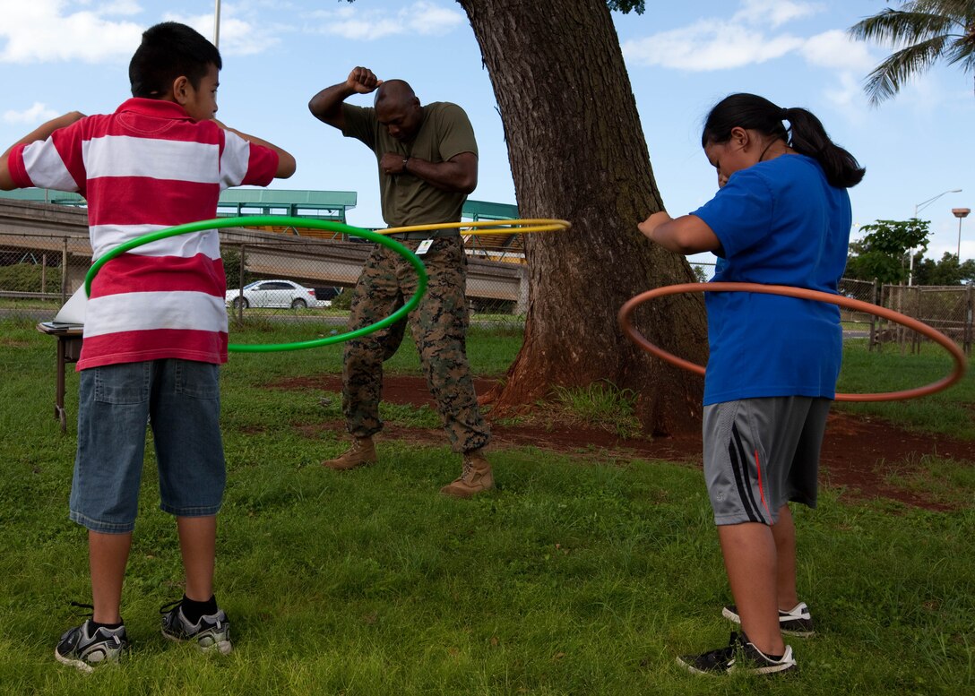 AIEA, Hawaii -Staff Sgt. Michael A. Johnson, company gunnery sergeant for Headquarters Company, Headquarters and Service Battalion, U. S. Marine Corps Forces, Pacific, hula hoops with Elementary School students March 8 at the school, here.
MarForPac Marines assisted the school’s physical education teacher with her classes as part of the command’s ongoing community service efforts. MarForPac officials plan to continue volunteering at numerous schools around the community.
