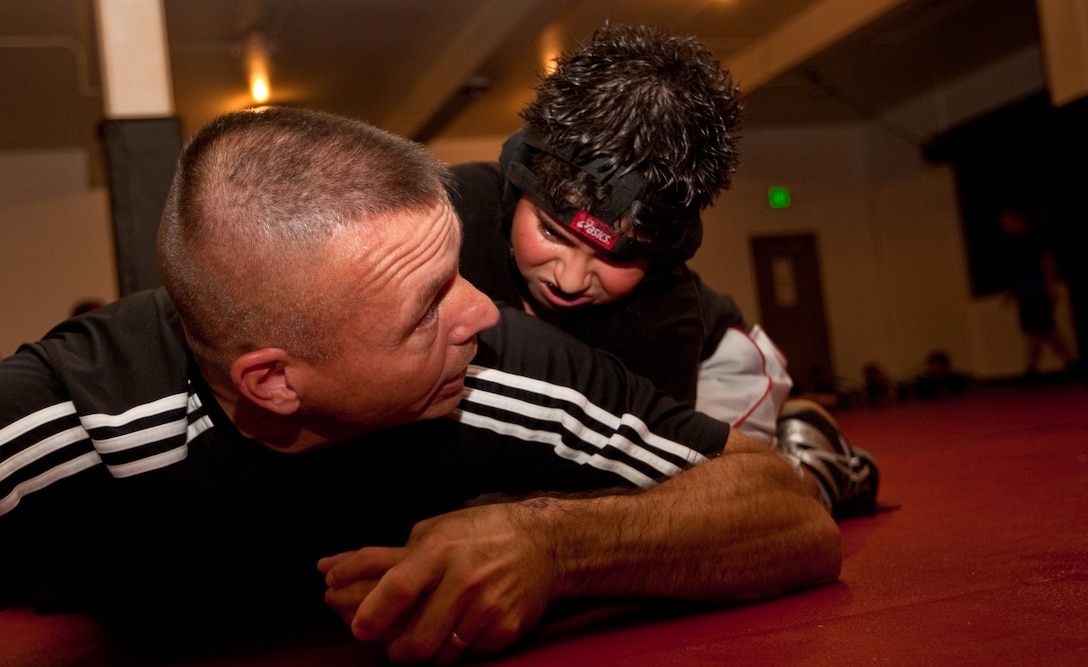 MARINE CORPS BASE HAWAII -Master Sgt. Timothy D. Greenleaf, war reserve chief, G-4, U.S. Marine Corps Forces, Pacific, shows one of his wrestlers how to defend against a half nelson during the physical conditioning portion of a two-hour wrestling practice April 11 at the Division Schools Martial Arts Center here. Greenleaf has spent the past 18 years coaching numerous youth sports teams and is currently the head coach for Marine Corps Base Hawaii’s Marine Corps Community Services youth wrestling team