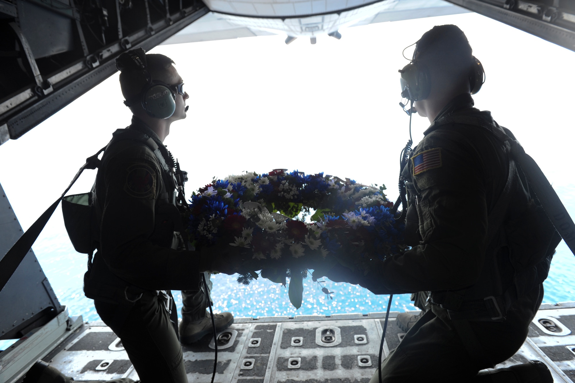 NEAR CAPONES ISLAND, Philippines -- Staff Sgts. David Wardell (left) and Ian Macgregor, both loadmasters with the 1st Special Operations Squadron, prepare to release a wreath in memorial of STRAY 59 while aboard an MC-130H Combat Talon II Feb. 26. The flight was to honor fallen brethren that were lost 31 years ago when a 1st SOS MC-130E, call sign STRAY 59, crashed during an exercise killing eight crew members and 15 passengers. (U.S. Air Force Photo by Airman 1st Class Brooke P. Beers)