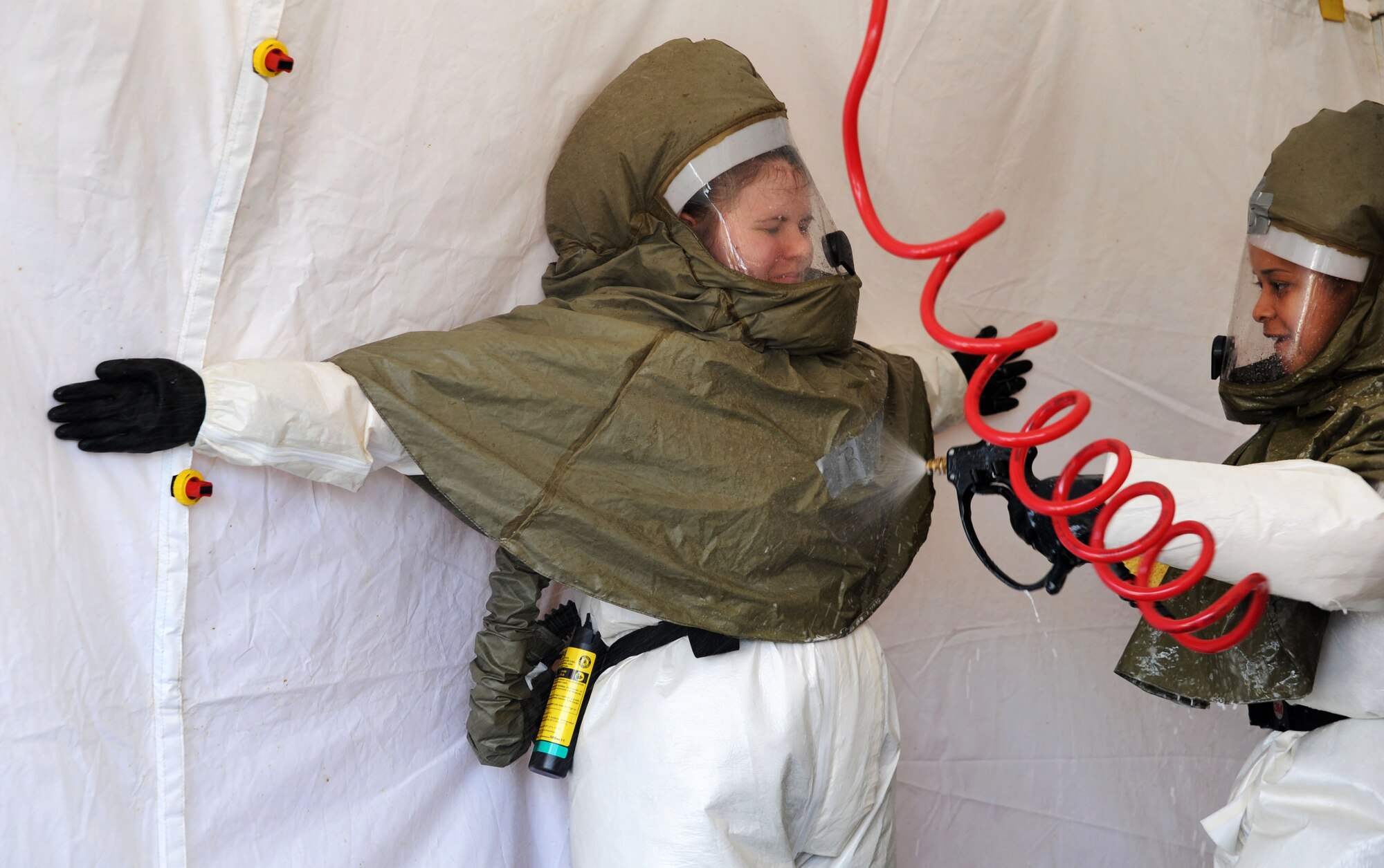 Staff Sgt. Satin Polanco sprays Staff Sgt. Stephanie Rowe with water during a timed trial to complete the In Place Patient Decontamination training at Joint Base Charleston - Air Base Feb. 23. The training is designed to prepare Airmen to provide care during a chemical, biological, radiological or nuclear catastrophe. Polanco is a 628th Medical Group physical therapy technician and Rowe is a 628th MDG dental assistant. (U.S. Air Force photo/Airman 1st Class Ashlee Galloway)