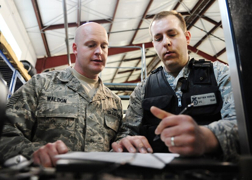 Tech. Sgt. Anthony Waldon assists Airman 1st Class Matthew Douglas with his paperwork during an inventory at the 628th Security Forces Squadron warehouse at Joint Base Charleston - Air Base Feb. 27. The warehouse coordinates daily, weekly and yearly accountability supply reports ensuring error free transaction processing for inventory totaling more than $3.2 million. Waldon is a 628th SFS supply non-commissioned officer in charge and Douglas is a 628th SFS journeyman. (U.S. Air Force photo/Staff Sgt. Katie Gieratz) 