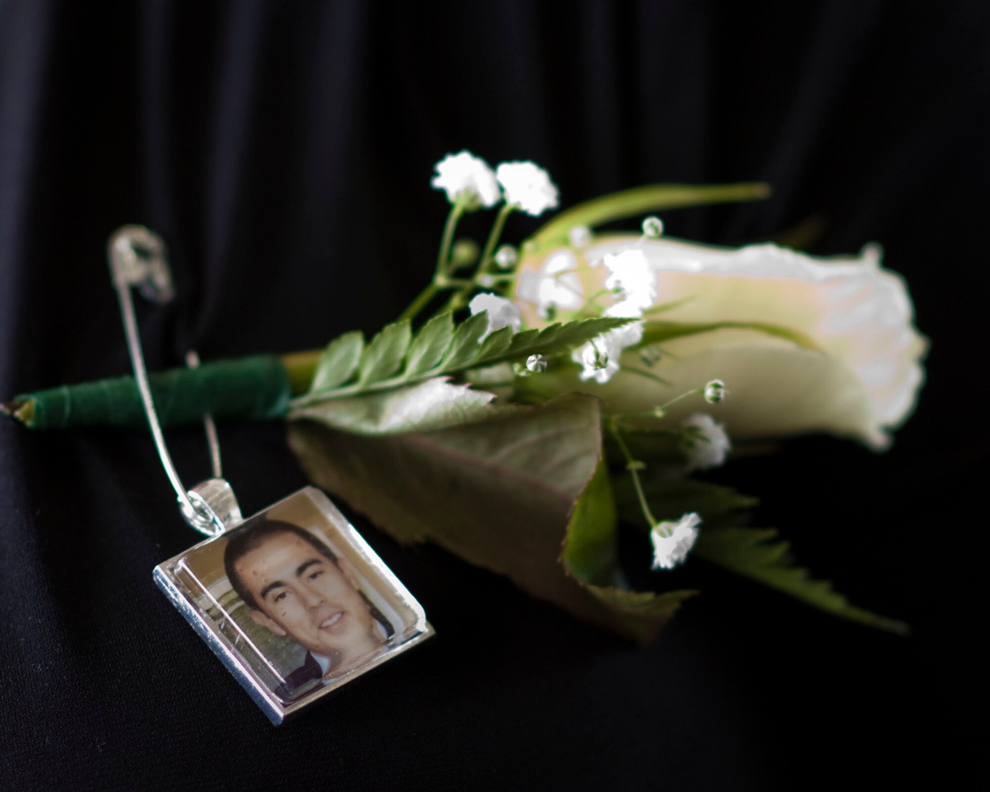 Senior Airman Julian S. Scholten's friends and family wear white boutonnieres adorned with Scholten's photo during a ceremony held at Hurlburt Field, Fla., Feb. 28, 2012, honoring him and three other Hurlburt Airmen killed in a Feb. 18, 2012, U-28A crash in Djibouti, Africa. (U.S. Air Force photo/Staff Sgt. Vanessa Valentine)(Released)