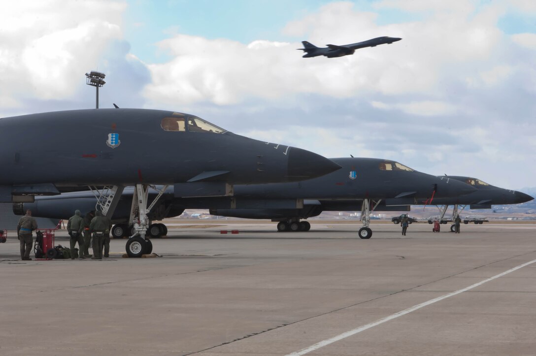 Aircrews from the 37th Bomb Squadron perform pre-flight checks as a B-1 bomber thunders overhead during an Operational Readiness Exercise on Ellsworth Air Force Base, S.D., Feb. 23, 2012. B-1B missions were conducted during the ORE that tested the base’s ability to rapidly mobilize and process assets during wartime contingencies. (U.S. Air Force photo by Airman 1st Class Zachary Hada/Released) 