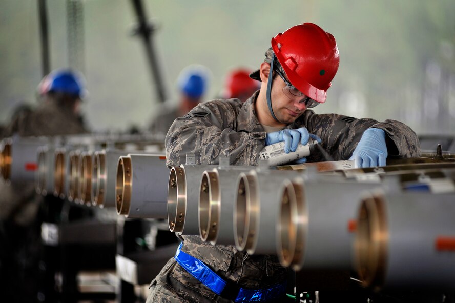 U.S. Air Force Senior Airman Daniel Stehley, 20th Equipment Maintenance Squadron munitions flight, spray paints build codes on inert guided bomb units after helping assemble each weapon, Feb. 27, 2012, Shaw Air Force Base, S.C. The weapons were assembled in preparation for an upcoming Operational Readiness Exercise. (U.S. Air Force photo by Senior Airman Kenny Holston/Released)