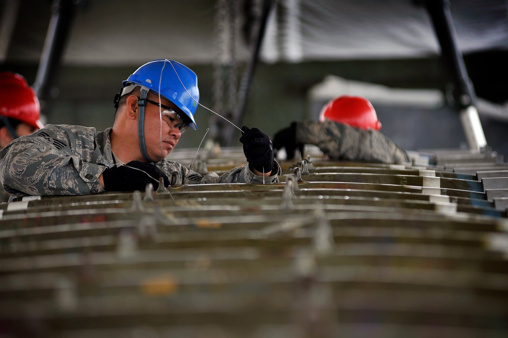 U.S. Air Force Staff Sgt. Juan Borja, 20th Equipment Maintenance Squadron munitions flight, stands in between several inert guided bomb units to get a better reach as he helps assemble each weapon, Feb. 27, 2012, Shaw Air Force Base, S.C. The weapons were assembled in preparation for an upcoming Operational Readiness Exercise. (U.S. Air Force photo by Senior Airman Kenny Holston/Released)

