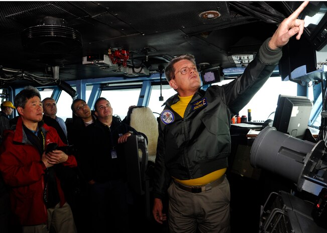 Capt. William Hamilton Jr., USS Enterprise (CVN 65) commanding officer, points to the ships navigation controls, Jan 16, 2012 during a Distinguished Visitors Embark aboard the air craft carrier. The ship was 75 miles of the coast of Florida and was conducting pre-deployment exercises. The Navy’s DV Embark program is designed to increase awareness of the Navy's mission by selecting community leaders to share their experiences with the largest possible audience. (Courtesy photo) 
