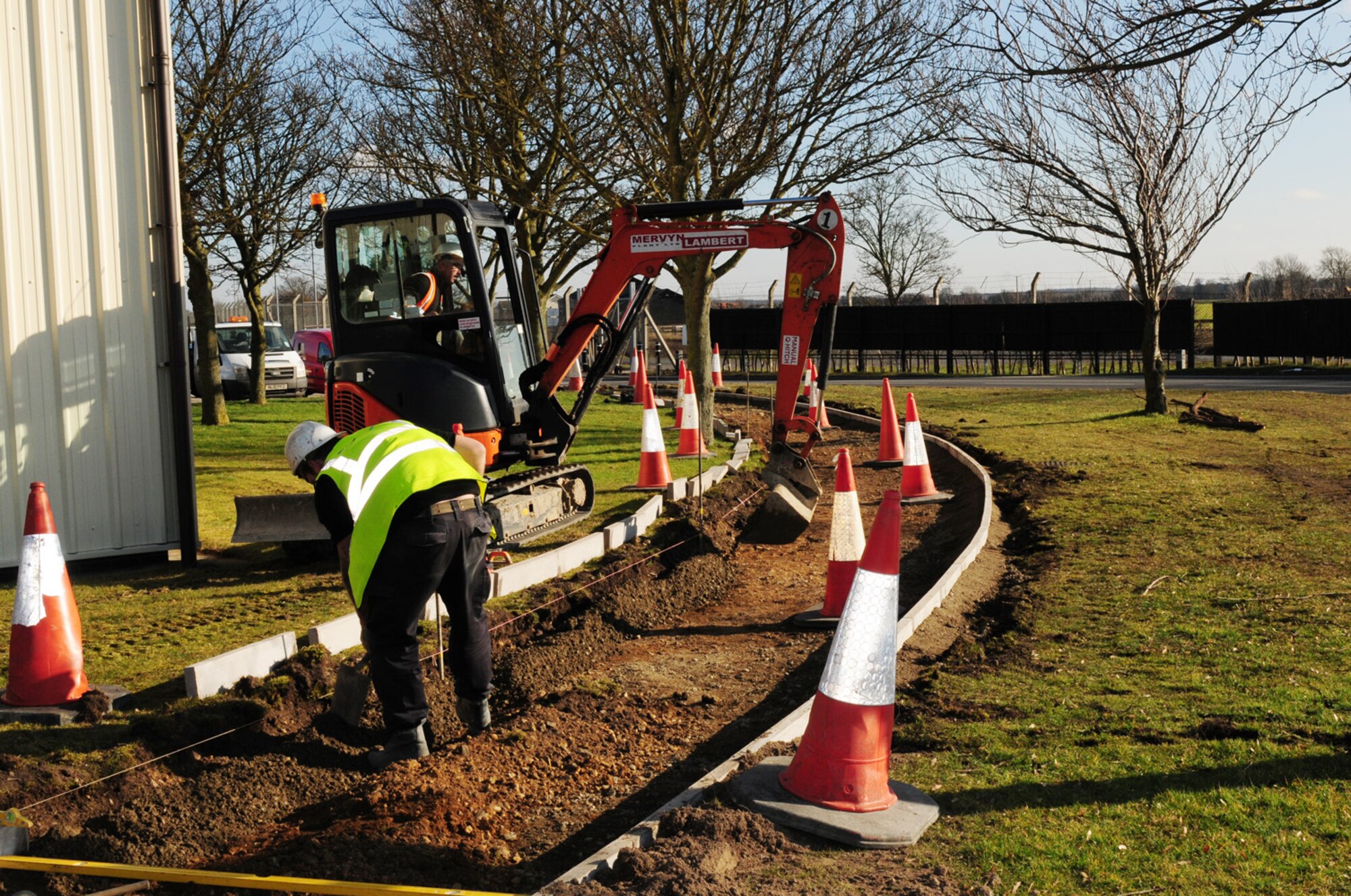 RAF MILDENHALL, England – A contractor digs out soil to lay path edging during the new running track construction Feb. 23, 2012. The running path will be more than 2-miles-long and almost 6-feet-wide, with the rubber surface being made from recycled car tires. This is one of five projects that have also benefitted from using recycled concrete from the demolition of Building 538. According to the 100th Civil Engineer Squadron, 10,000 tons of materials have been recycled to date, saving about $314,000. The running path is scheduled for completion in June. (U.S. Air Force photo/Karen Abeyasekere)