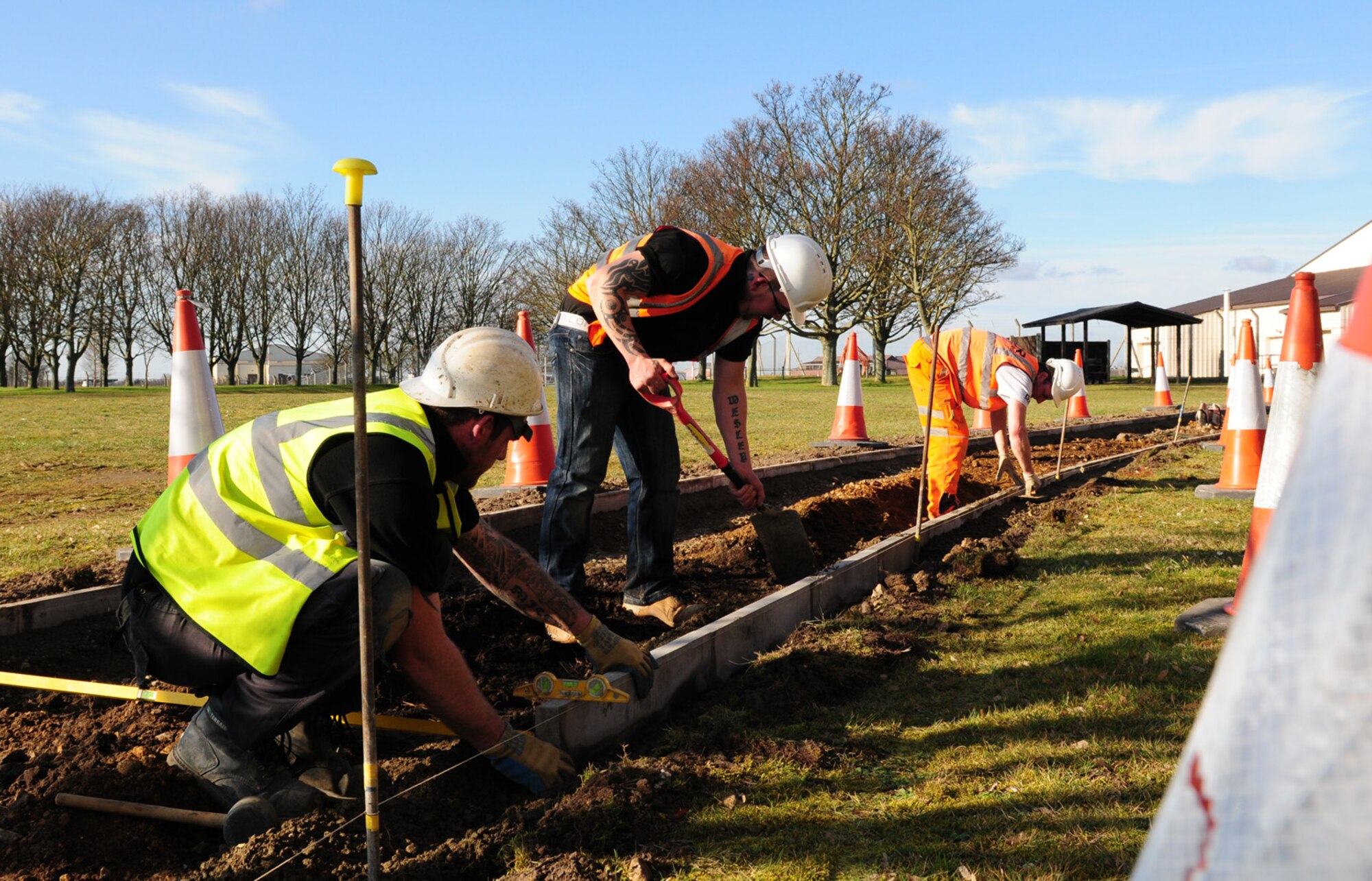 RAF MILDENHALL, England – Contractors Gary Congreve, Simon Santos and John Howarth, dig and lay path edgings on the new running track Feb. 23, 2012, on the south side of base. The construction project for the path uses recycled, crushed concrete from the demolition of Building 538, and will also use recycled rubber for the top surface. Costing more than $634,000, the running path is about 2-miles-long, will be almost 6-feet-wide and is scheduled for completion in June. (U.S. Air Force photo/Karen Abeyasekere)