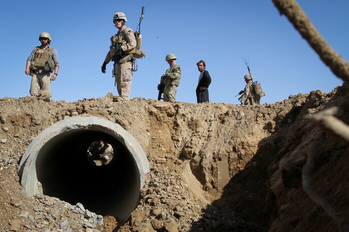 Capt. Jesse Hills, the team leader of Team 3, Civil Affairs Detachment 11-2, peeks through a newly placed culvert in a road just outside of Combat Outpost Castle in Khan Neshin, Afghanistan, Feb. 29, 2012. Travis Burke, a United States Agency for International Development field program officer, and Sgt. Andrew Sanford, a member of Team 3, inspected the canal the culvert will serve during the site survey patrol. The culvert is part of a road-paving project initiated by Team 3. Hills is a 28-year-old from Terre Haute, Ind., Burke is a native of Reno, Nevada, and Sanford is a 24-year-old from Costa Mesa, Calif.