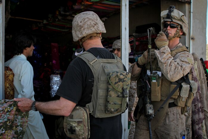 Second Lt. Andrew McGann, the assistant team leader of Team 3, Civil Affairs Detachment 11-2, pauses a patrol in order to help an American contractor buy goods from a merchant in Khan Neshin, Afghanistan, Feb. 29, 2012. McGann is a 26-year-old native of Longmont, Colo., serving a seven-month deployment to Afghanistan.
