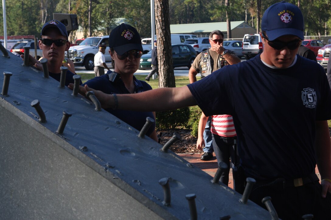 Members of the Half Moon Fire Department pay their respects at the Memorial Beam in the Lejeune Memorial Gardens following the Patriot Day 2011 ceremony, marking the 10th anniversary of the Sept. 11, 2011 terrorist attacks, at the Memorial Beam in Lejeune Memorial Gardens, Sept. 11. Of the near 3,000 people who lost their lives that day, among them were first responders from the New York Fire Department, disregarding their personal safety to come to the aid of those in and around the World Trade Center.