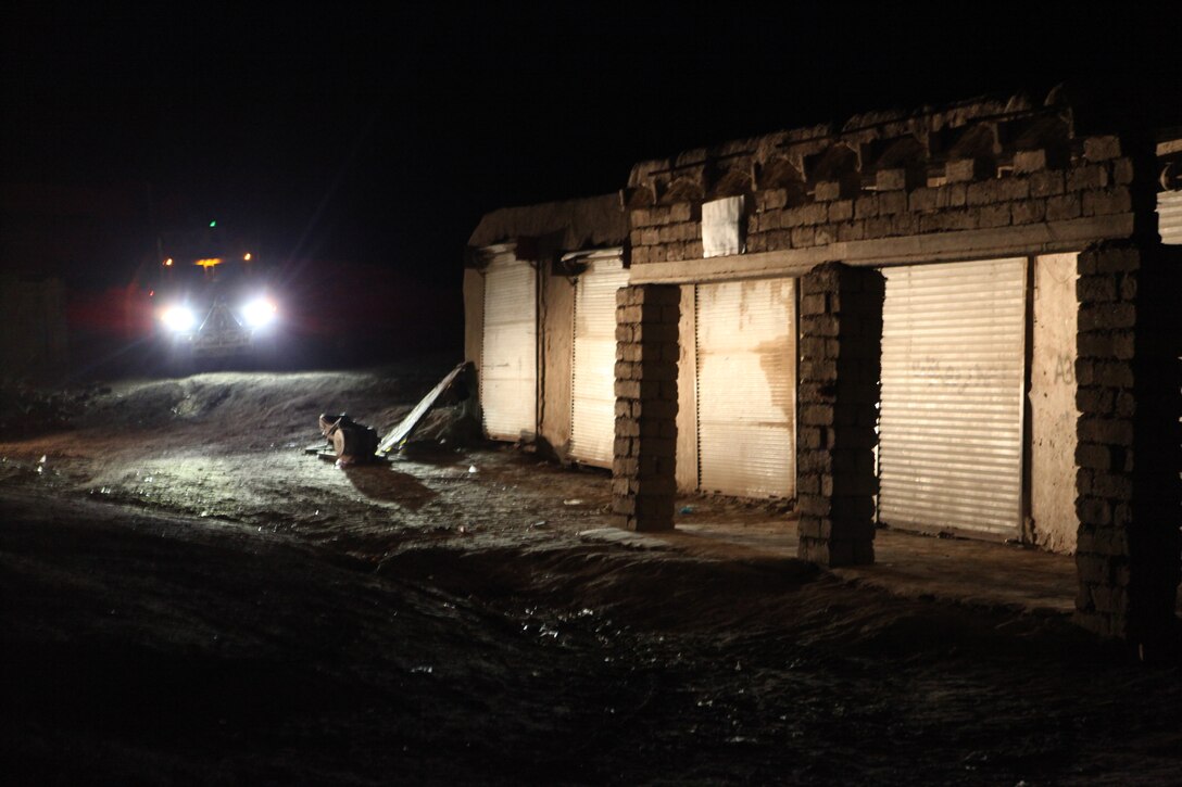 A Mine Resistant Ambush Protected (MRAP) vehicle from Bridge Platoon, Alpha Company, 9th Engineer Support Battalion, 1st Marine Logistics Group (Forward) illuminates the bazaar near the town of Shir Ghazay during a bridge replacement project, Feb. 29.  The local Afghans became concerned over the safety of the bridge after the weather had damaged the structure. In response, the Marines of 9th ESB replaced it with a more permanent solution.