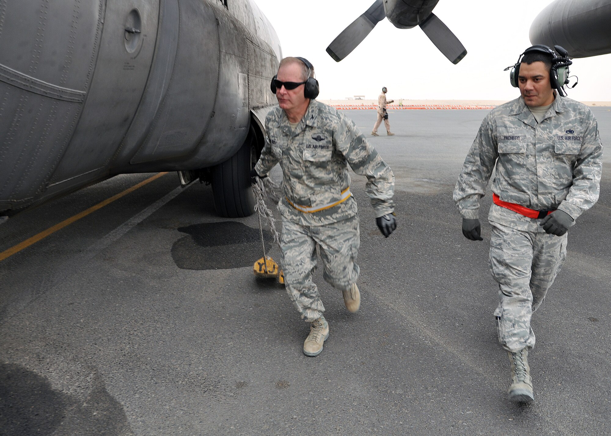 SOUTHWEST ASIA -- Col. Michael Zick, 386th Air Expeditionary Wing commander, pulls the parking chalks of a C-130 Hercules until the watchful eye of Staff Sgt. Julian Pacheco, 386th Expeditionary Aircraft Maintenance Squadron crew chief, before the first flight of the new year, Jan. 1, 2012.  Zick volunteered to be an honorary crew chief for 2012’s initial sortie, pulling parking chalks and marshalling the aircraft out of its parking spot and onto the flightline prior to takeoff. (U.S. Air Force photo/Tech. Sgt. Stacy Fowler) 