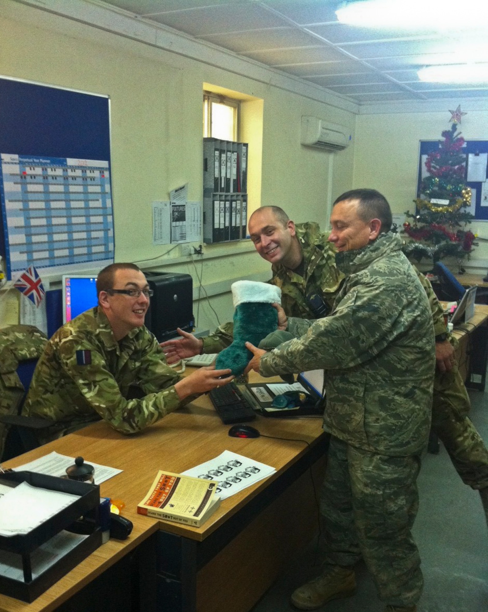 KANDAHAR AIRFIELD, Afghanistan -- From right, Chaplain (Capt.) Kevin Humphrey, a 451st Air Expeditionary Wing chaplain, gives a stocking to a Royal Air Force service member at Kandahar Airfield, Afghanistan, Dec. 21, 2011. Humphrey and his team of volunteers received more than 3,400 stockings to give to fellow Airmen and coalition partners at Kandahar. (Courtesy photo)