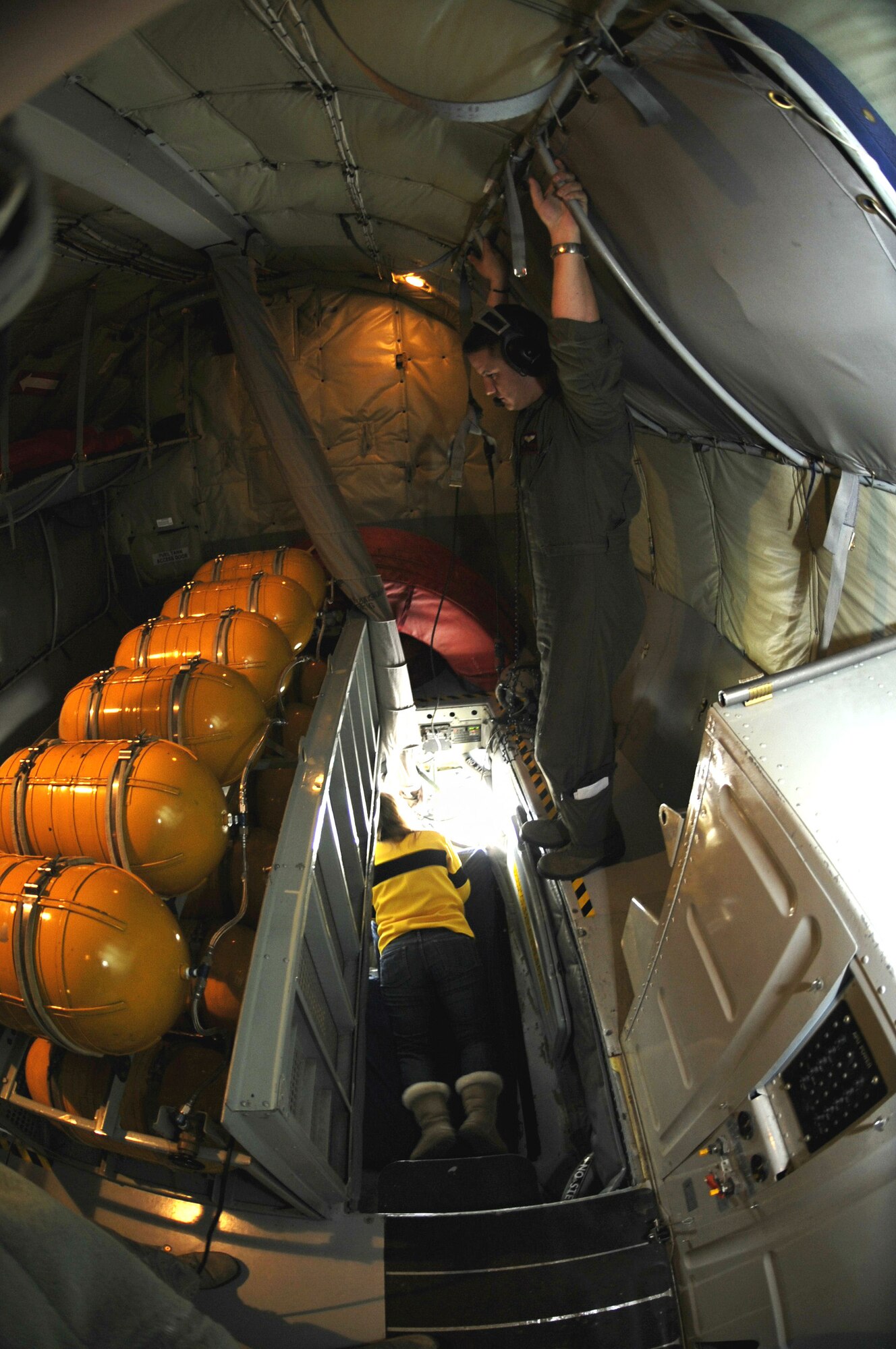 Capt. Chad Winters, 909th Air Refueling Squadron pilot from Kadena Air Base, Japan, stands watch as spouses observe beside a boom operator on a refueling training mission, Dec. 28, 2011, off the coast of the Republic of Korea. Military spouses visiting the area were given the opportunity to fly on a KC-135 Stratotanker to see part of the Air Force mission and get a taste of the work their spouses do every day. (U.S. Air Force photo by Senior Airman Jessica Hines/Released)