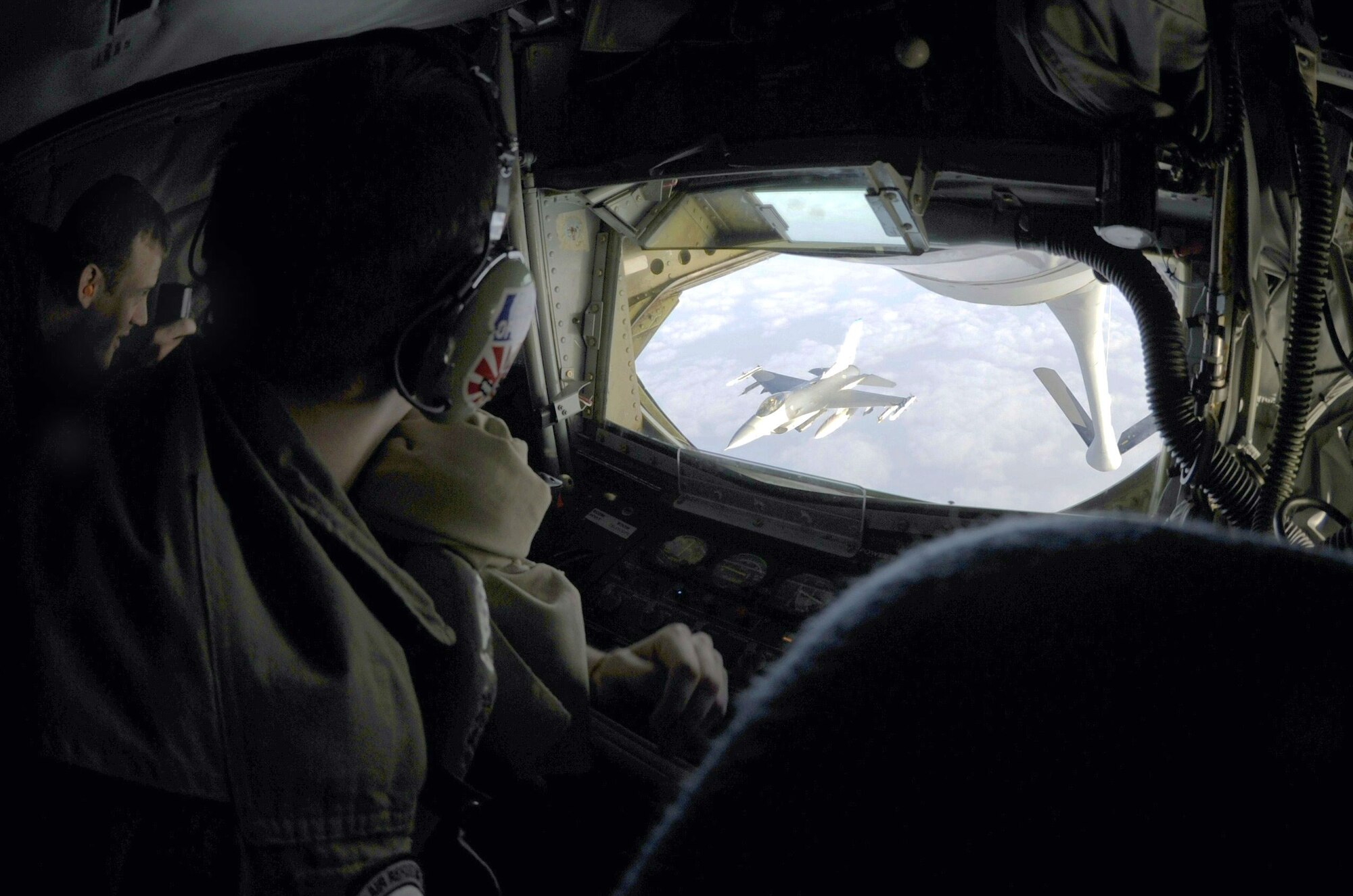 A military spouse and boom operator watch as an F-16 Fighting Falcon from the 35th Fighter Squadron departs a KC-135 Stratotanker of the 909th Air Refueling Squadron from Kadena Air Base, Japan, after receiving fuel as part of a refueling training mission off the coast of the Republic of Korea, Dec. 28, 2011. As part of a joint effort between the 8th Fighter Wing and the 909th ARS, military spouses visiting the ROK were given the opportunity to fly on the air refueling mission. (U.S. Air Force photo by Senior Airman Jessica Hines/Released)