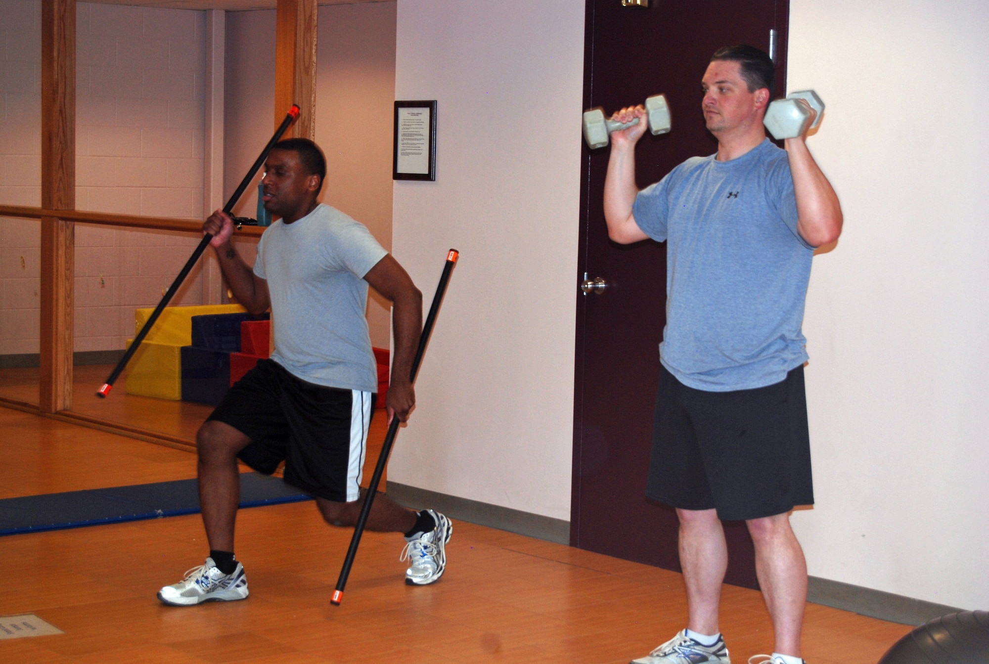 Participants in the Domination Boot Camp class do lunges and an overhead press during a circuit training workout. After six months of the program at Kadena Air Base, Japan, Physical Fitness Test scores increased an average of 16.9 points for individuals who attended four to five times a week and an average of nine points for those who attended three days a week. (U.S. Air Force photo/Lea Johnson)