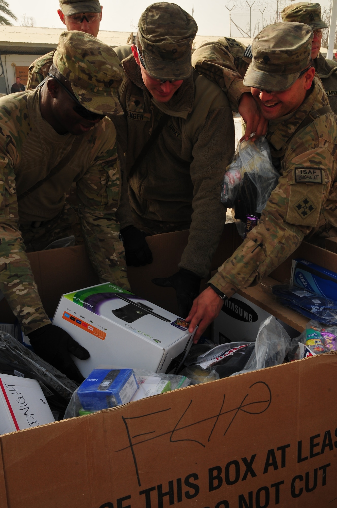 Soldiers from Task Force Bison pull an XBOX 360 from a USO donated gift box at Camp Nathan Smith, Dec. 23. The gifts were donated by the USO and delivered by Task Force Resolute during Operation Christmas Convoy. (U.S. Army photo by Staff Sgt. Alexander Burnett)
