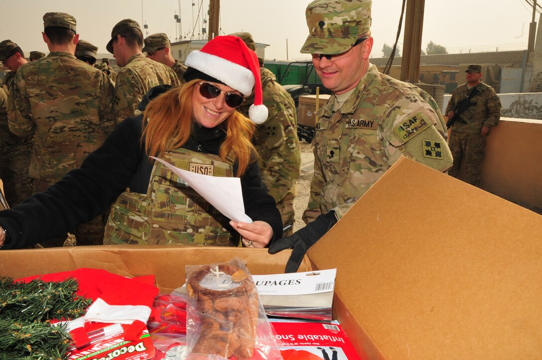Priya Butler, left, the USO director of operations for Southwest Asia, shows Spc. Torrence Hall, a cavalry scout assigned to Headquarters and Headquarters Troop, Task Force Bison, the holiday decorations for his unit donated by the USO during Operation Christmas Convoy at Camp Nathan Smith, Dec. 23. Operation Christmas Convoy delivered gifts to Soldiers on remote forward operating bases for the holiday season. (U.S. Army photo by Staff Sgt. Alexander Burnett)