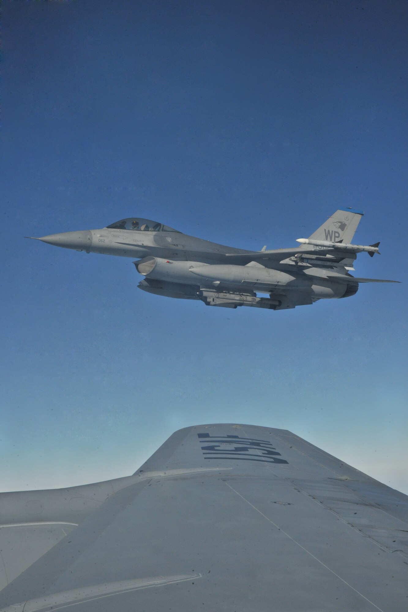 An F-16 Fighting Falcon coasts beside a KC-135 Stratotanker of the 909th Air Refueling Squadron from Kadena Air Base, Japan, as part of a refueling training mission off the coast of the Republic of Korea, Dec. 28, 2011. As part of a joint effort between the 80th Fighter Squadron and the 909th ARS, military spouses visiting the area were given the opportunity to fly on the KC-135 during the air refueling.  (U.S. Air Force photo by Senior Airman Brittany Y. Auld/Released)