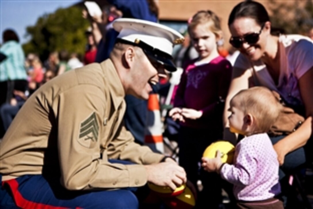 A Marine gives a football to a baby during the Fiesta Bowl Parade in Phoenix, Dec. 31, 2011. Marines walked in the parade, handing out footballs and information about the Semper Fidelis All American Bowl, which features the nation’s top 100 senior football players.