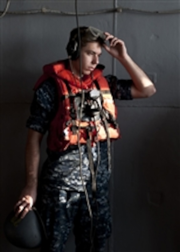 Seaman Seth Coulter dons protective gear before a replenishment at sea aboard the aircraft carrier USS John C. Stennis (CVN 74) in the Arabian Sea on Dec. 29, 2001.  The John C. Stennis is deployed to the U.S. 5th Fleet area of responsibility conducting maritime security operations and support missions as part of Operation Enduring Freedom.  