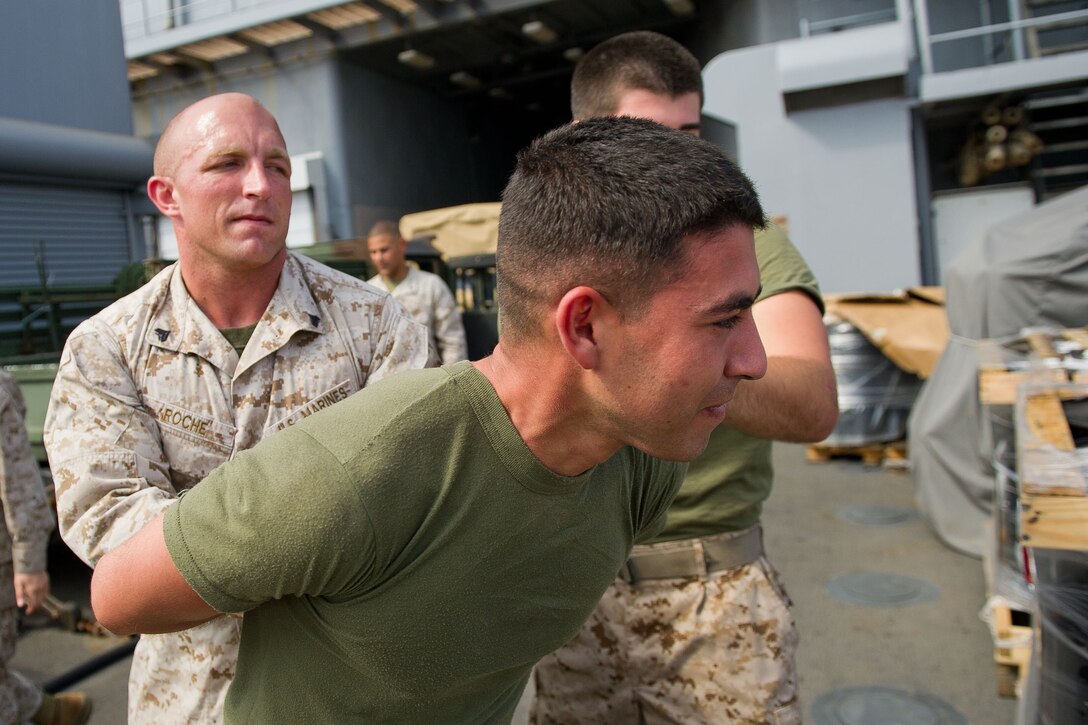 Cpl. Jonathan Roche, 26, escorts a simulated detainee aboard USS Pearl Harbor (LSD 52) during a noncombatant evacuation drill Jan. 3. Roche, a Chicago native, serves with Combat Logistics Battalion 11, which provides logistics and services for the 11th Marine Expeditionary Unit. The 11th MEU is currently deployed as part of the Makin Island Amphibious Ready Group (MKIARG) as the U.S. Central Command theater reserve force, also providing support for maritime security operations and theater security cooperation efforts in the U.S. 5th Fleet area of responsibility.