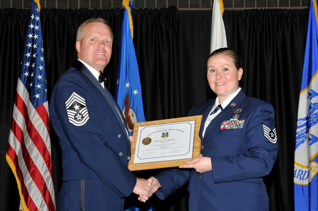 McGHEE TYSON AIR NATIONAL GUARD BASE, Tenn. -- Tech. Sgt. Sara J. Bishop, right, receives the distinguished graduate award for NCO Academy Class 11-8 at The I.G. Brown Air National Guard Training and Education Center here from Command Chief Master Sgt. Kevin Candler, Nov. 3, 2011.  The distinguished graduate award is presented to students in the top ten percent of the class.  It is based on objective and performance evaluations, demonstrated leadership, and performance as a team player. (U.S. Air Force photo by Master Sgt. Kurt Skoglund/Released)