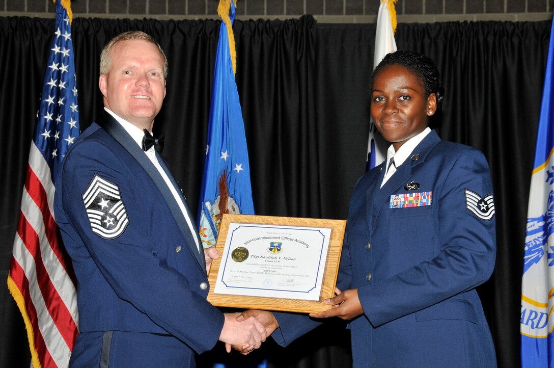 McGHEE TYSON AIR NATIONAL GUARD BASE, Tenn. -- Tech. Sgt. Khalilah V. Nelson, right, receives the distinguished graduate award for NCO Academy Class 11-8 at The I.G. Brown Air National Guard Training and Education Center here from Command Chief Master Sgt. Kevin Candler, Nov. 3, 2011.  The distinguished graduate award is presented to students in the top ten percent of the class.  It is based on objective and performance evaluations, demonstrated leadership, and performance as a team player. (U.S. Air Force photo by Master Sgt. Kurt Skoglund/Released)