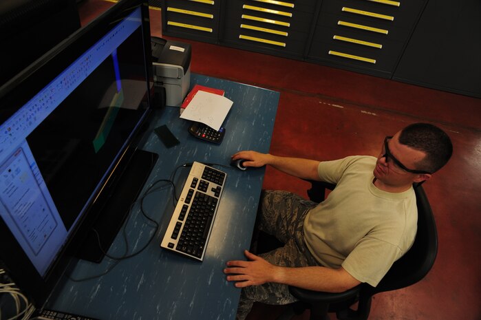 Master Sgt. George Greene enters information into the computer automated drafting/manufacturing program which will then filter more information to the Computer Numeric Control milling machine at Joint Base Charleston - Air Base Dec. 15. The CNC milling machine uses the data to create a fixture to hold aircraft parts. Greene is the aircraft metals technology section chief with the 437th Maintenance Squadron. (U.S. Air Force photo/Staff Sgt. Katie Gieratz)