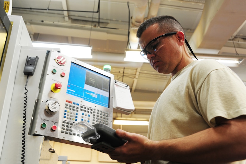 Master Sgt. George Greene enters information into the Computer Numeric Control milling machine at Joint Base Charleston - Air Base Dec. 15. The CNC milling machine uses the data to create a fixture to hold aircraft parts. Greene is the aircraft metals technology section chief with the 437th Maintenance Squadron. (U.S. Air Force photo/Staff Sgt. Katie Gieratz) 