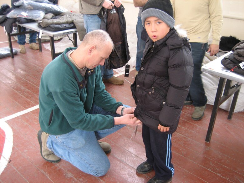 Lt. Col. Adam Rutherford helps a Kyrgyz child find a coat that fits Dec. 28, 2011, at one of the five distribution sites during an “Operation Warm and Dry” event in Kyrgyzstan. The Transit Center in Manas, the Kyrgyz Republic and the U.S. Embassy sponsor "Operation Warm and Dry".Rutherford is from Peterson Air Force Base, Colo. (U.S. Air Force Courtesy photo) 
