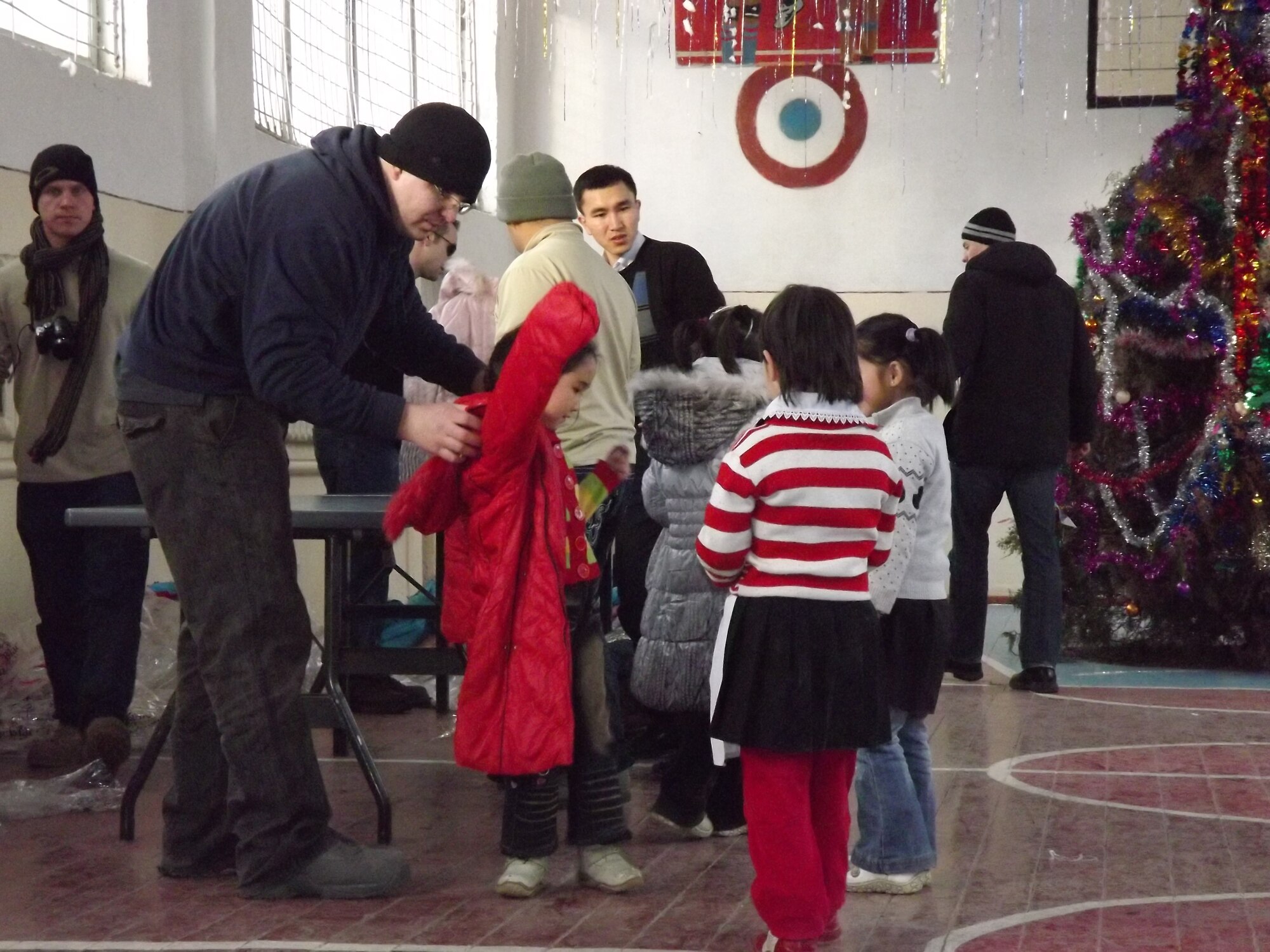 Staff Sgt. John Marshall puts a coat on a Kyrgyz child Dec. 28, 2011, during an “Operation Warm and Dry” event in Kyrgyzstan. The Transit Center in Manas, the Kyrgyz Republic and the U.S. Embassy sponsor "Operation Warm and Dry". Marshall is deployed to the Transit Center at Manas from Spangdahlem Air Base, Germany(U.S. Air Force Courtesy photo) 