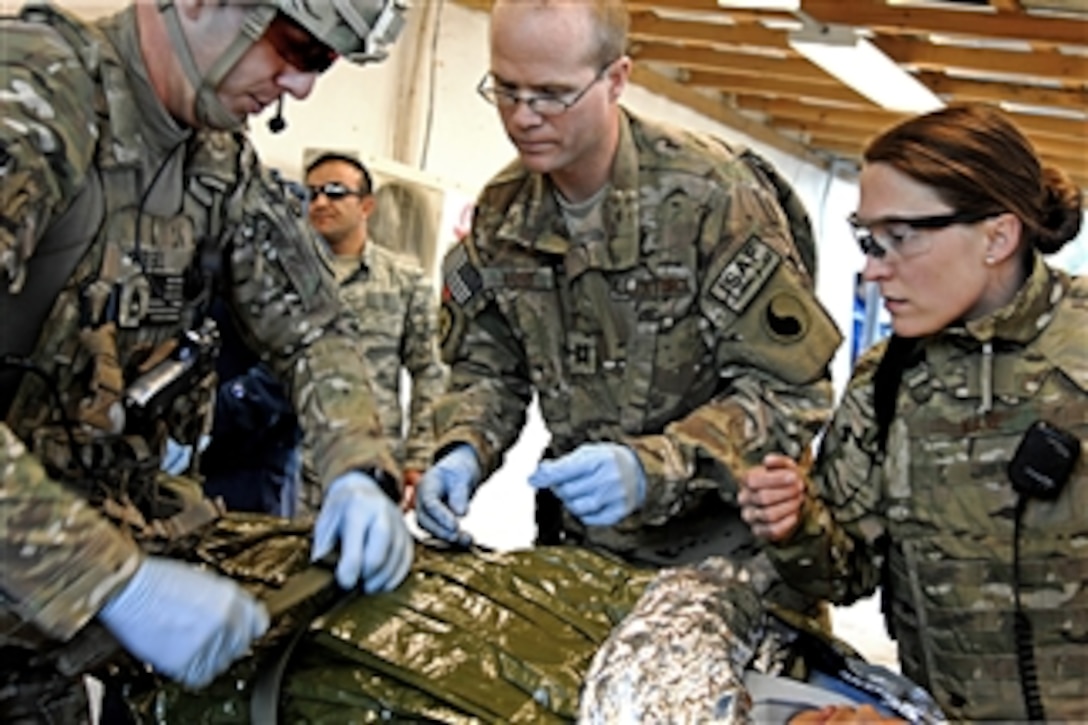 U.S. Army Sgt. 1st Class Robert Russell and U.S. Air Force Capts. Michael Madsen and Leslee Kane provide emergency medical treatment for an Afghan National Police member at Forward Operating Base Smart, Afghanistan, on Dec. 25, 2011.  Russell is the platoon sergeant and Madsen and Kane are doctors assigned to Provincial Reconstruction Team Zabul.  