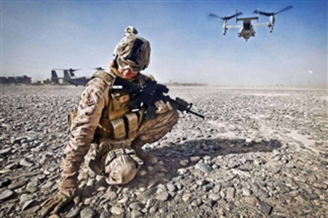 U.S. Marine Corps Cpl. William Cox shields himself from flying rocks and sand as an MV-22 Osprey aircraft prepares to take off in Nimroz province, Afghanistan, on Dec. 30, 2011.  Cox is an armorer assigned to the Joint Sustainment Academy Southwest.  