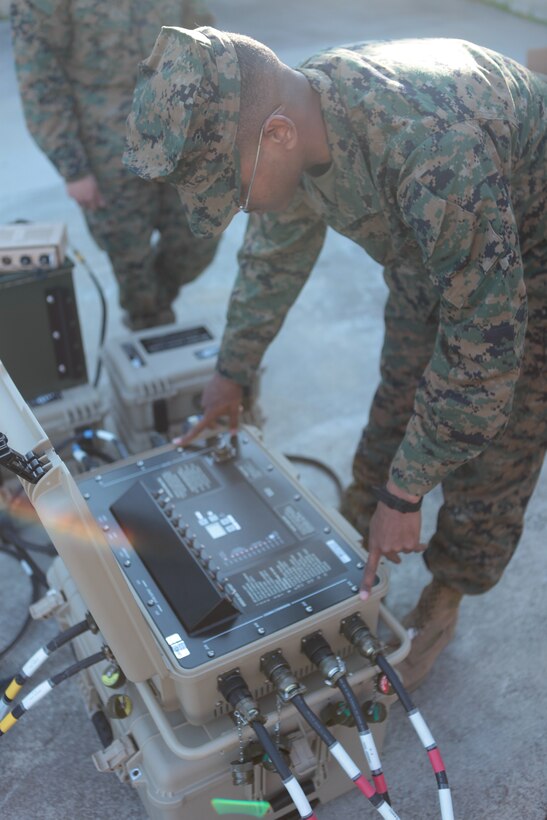 Cpl. Joshua Byrd, a field radio operator with Headquarters Company, 8th Marine Regiment, 2nd Marine Division, does a functions check on the control box of a Ground Renewable Expeditionary Energy Network System, which manages the number of solar panels energy is being pulled from, as well as which lithium batteries are being charged.