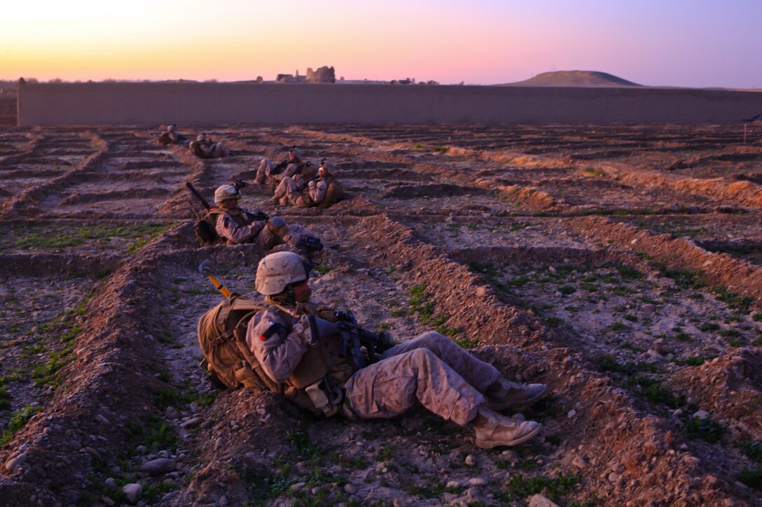 Marines with Echo Company, 2nd Battalion, 4th Marine Regiment, take a break from patrolling as the sun begins to rise.  The Marines, along with their Afghan Uniformed Police counterparts, began clearing one of their objectives for Operation Double Check at 2 a.m. and only rested when Explosive Ordinance Disposal Marines would stop the operation to investigate a potential threat.