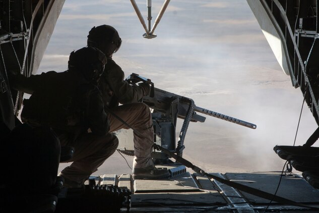 U.S. Marine Corps Cpl. Zachary Hughes (foreground), weapons tactics instructor, Marine Heavy Helicopter Squadron 363, observes Lance Cpl. Madison DeLoach operate a .50-caliber machine gun, Helmand River Valley, Helmand Province, Afghanistan, Jan. 5, 2011. DeLoach operated the .50-caliber machine gun during flight operations with the guidance of Hughes. (U.S. Marine Corps photo by Lance Cpl. Robert R. Carrasco/Released).