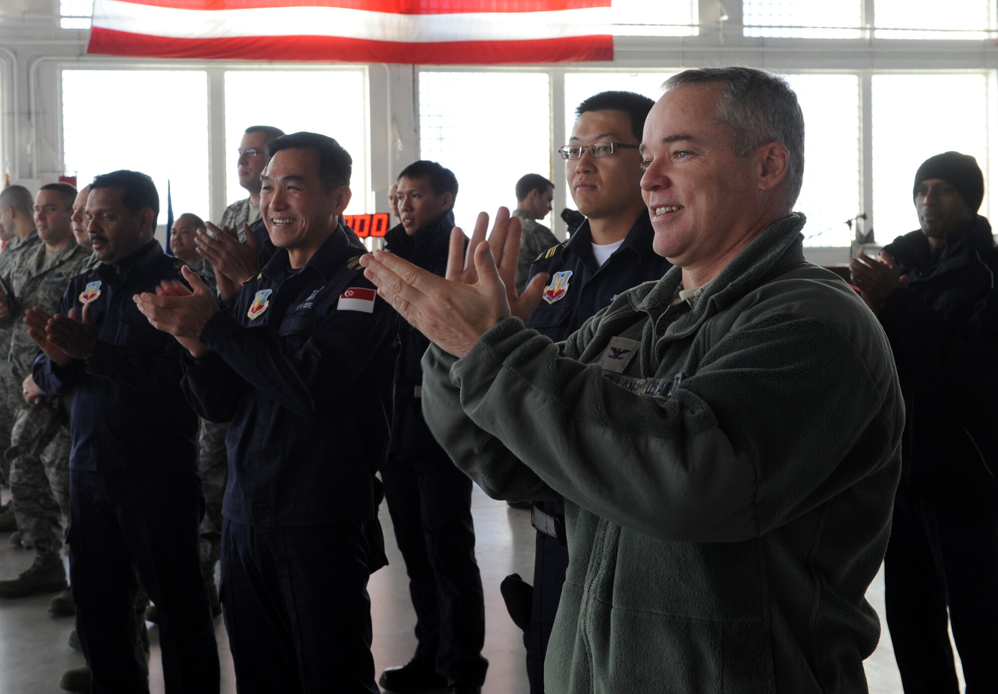 Col. James McClellan, 366th Maintenance Group commander, and Republic of Singapore Air Force 428th Fighter Squadron members applaud members of the weapon load crew teams during a quarterly competition Jan. 4, 2012, at Mountain Home Air Force Base, Idaho. Each team competes in an inspection of equipment, a written test, timed loading evaluation, and dress and appearance. (U.S. Air Force photo by Senior Airman Debbie Lockhart)