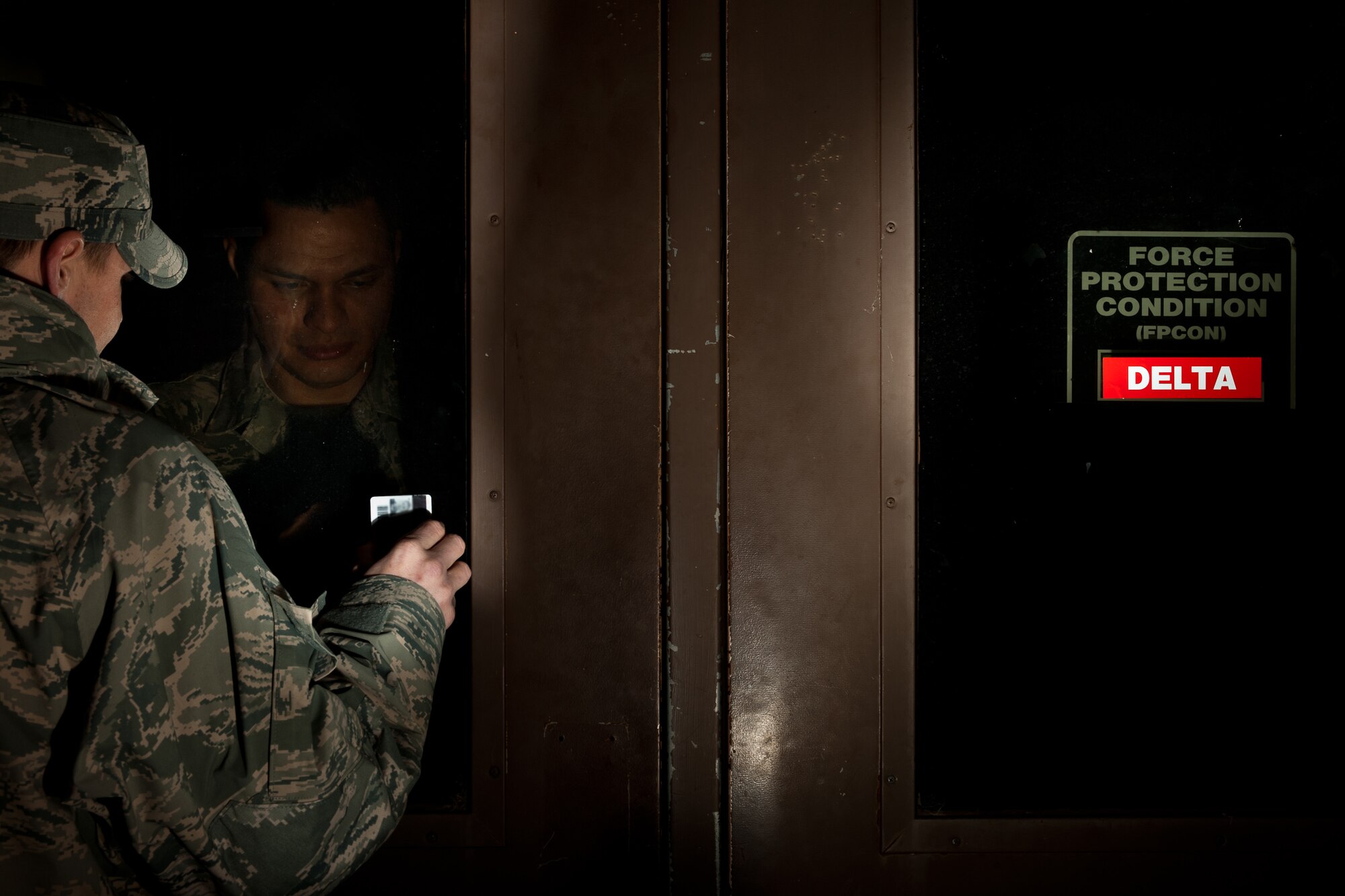 Senior Airman Santos Rodriguez, 28th Communications Squadron client systems technician, checks the identification card of Senior Airman Bradley Barnes, 28th Bomb Wing ground safety technician, prior to allowing him entry to the 28th BW Headquarters building on Ellsworth Air Force Base, S.D., Dec. 14, 2011. Whenever a Force Protection Condition changes, regardless of whether it’s during an exercise or not, it is a real world change and all measures must be obeyed. (U.S. Air Force photo by Airman Alystria Maurer/Released)