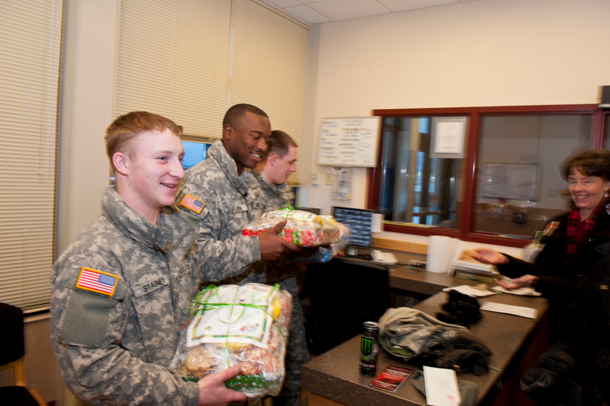 JOINT BASE ELMENDORF-RICHARDSON, Alaska -- From left, Spc. William Stasney, Sgt. Xaviar Green, and Pvt. Adam Hawkins, all of the 84th Expeditionary Support Company (Airborne), 6th Engineer Battalion, recieve holiday platters filled with cookies and fruit, from Margart Ames, one of the volunteers with the Armed Services YMCA, Dec. 20. (U.S. Air Force photo/Johnathon Green)